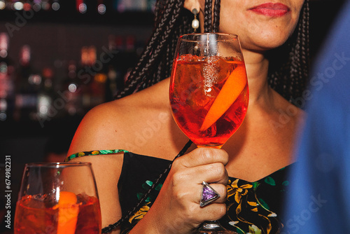 Woman with braids holding a drink at a club close up