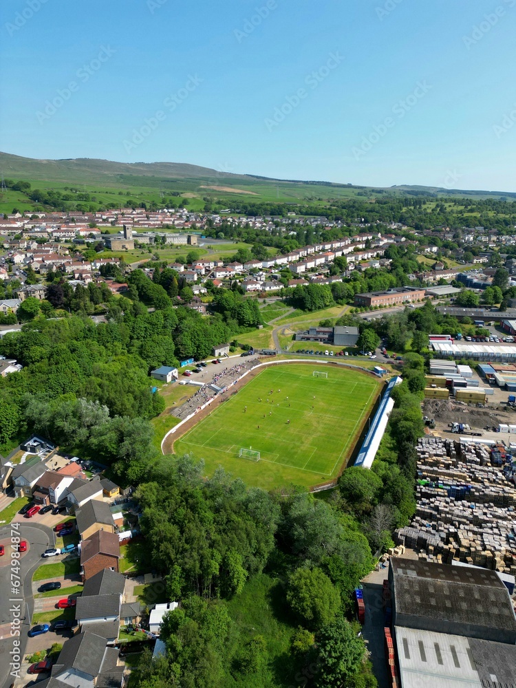 Vertical shot of a rural village in Scotland, with a gleaming football stadium in the foreground