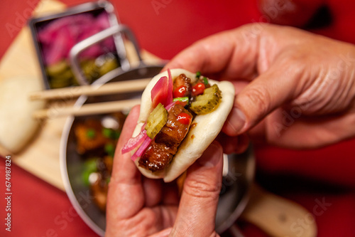 Man holding bao oriental sandwich vlose up red background top view photo