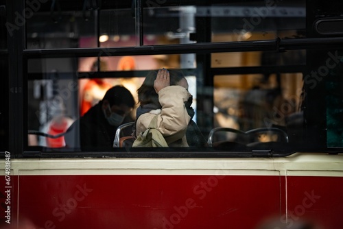 Cheerful young woman in her twenties is seated on a public bus, fixing her hair