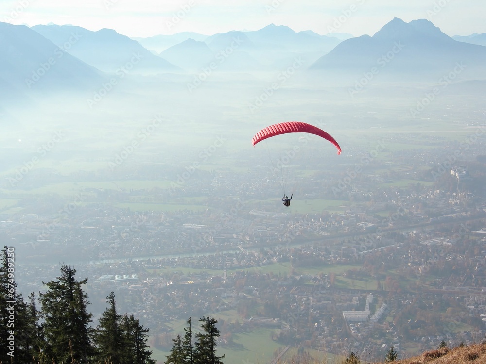 Paraglider soaring in the sky over the town and mountains. Paraglider soaring in the sky over the town and mountains.
