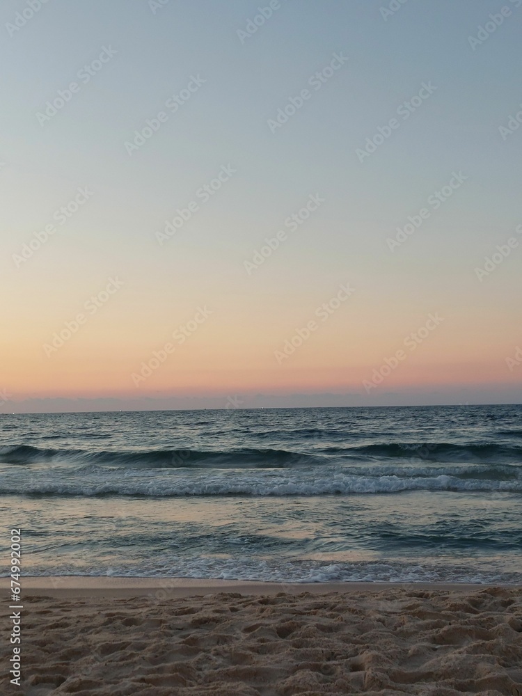 Beach scene featuring a beautiful sunset with rolling waves in the foreground