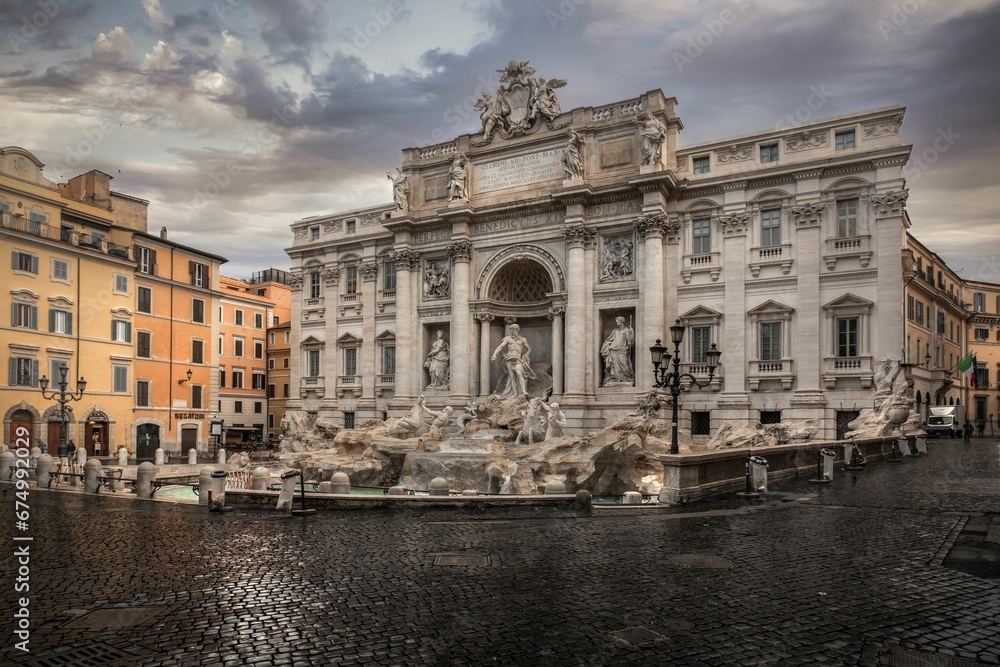 Dramatic evening shot of the Trevi Fountain in Rome, Italy with a cloudy sky in the background