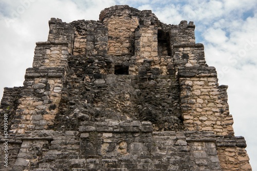 Image of the ancient Mayan ruins taken from a low angle, set against a cloudy sky