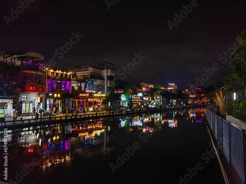 many shops are lit up at night on the water canal