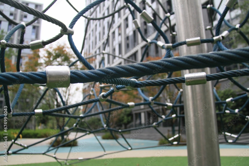 A play area, featuring a climbing net and a turf lawn grass A play area, featuring a climbing net and a turf lawn grass