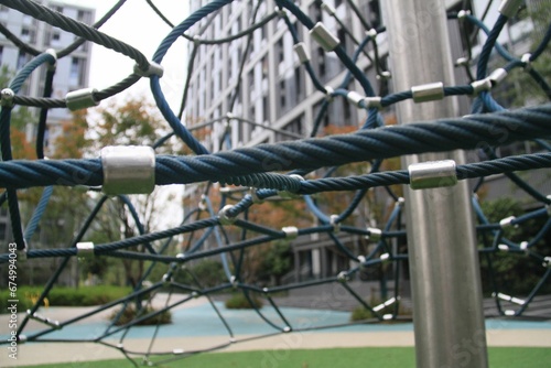 A play area, featuring a climbing net and a turf lawn grass