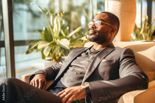 Portrait of wealthy and successful African American man, wearing stylish designer clothing and relaxing in a luxury condo, enjoying a moment