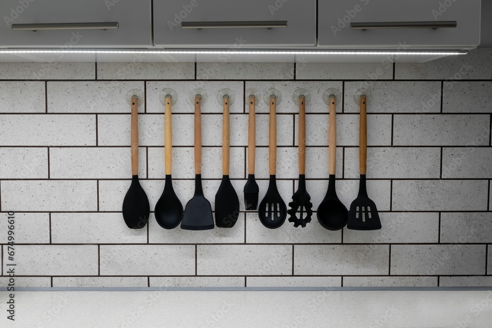 Closeup of a collection of silicon kitchenware hanging on a wall - obrazy, fototapety, plakaty 