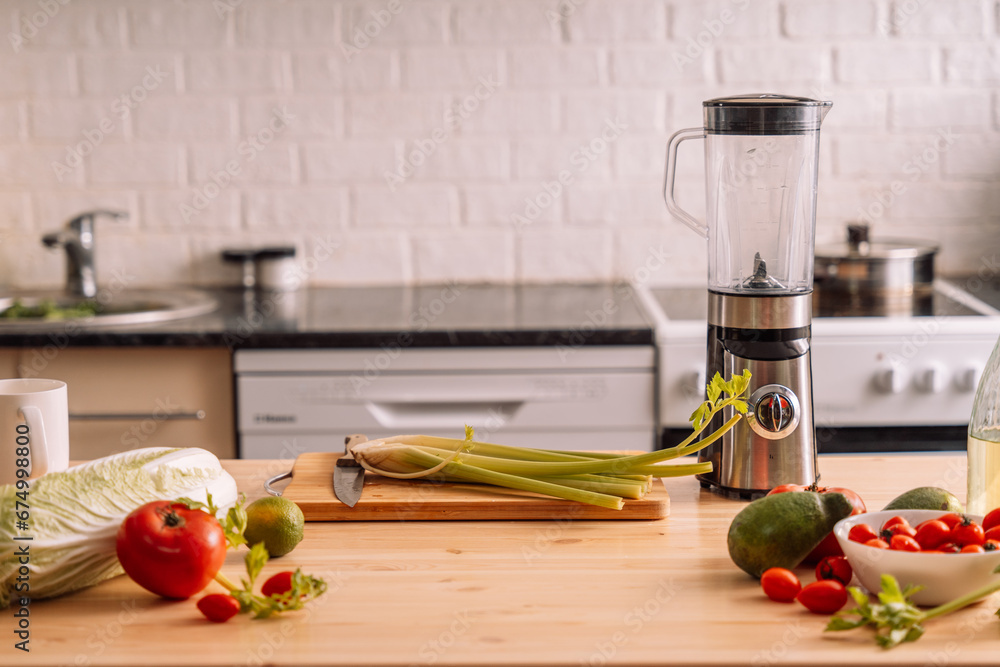 © Anastassiya  - Fresh vegetables with a blender on a wooden table in front of the kitchen.
