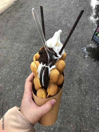 Closeup of a hand holding a bubble waffle ice cream with a cookie. photo