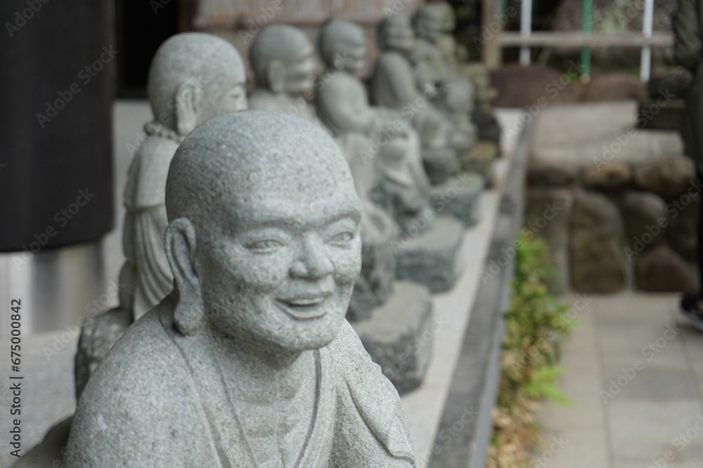 Array of Buddhist sculptures crafted from a stone line the path in a scenic outdoor setting