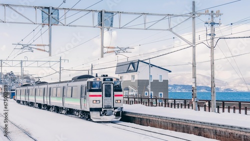 Scenic winter scene of a snow train passing through Asato, Hokkaido, Japan.