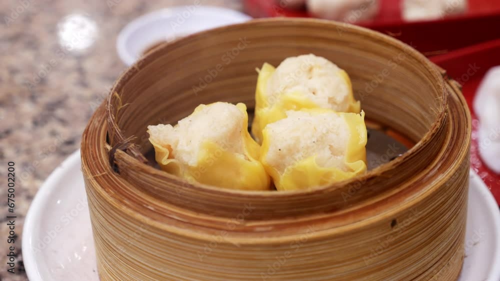 Picking a steaming dumpling using chopsticks and dipping it into a spicy sauce, while eating in a Chinese restaurant in Bangkok, Thailand. Picking a steaming dumpling using chopsticks and dipping it into a spicy sauce, while eating in a Chinese restaurant in Bangkok, Thailand.