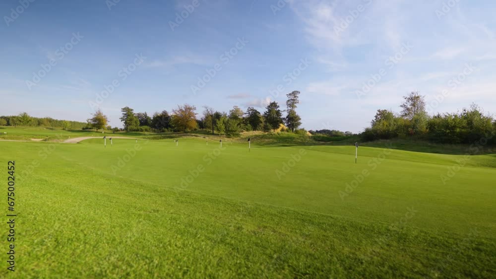 Empty Golf course, No golfers on the fairway. Flags on the golf hole - Cinematic travel shot with blue sky Empty Golf course, No golfers on the fairway. Flags on the golf hole - Cinematic travel shot with blue sky