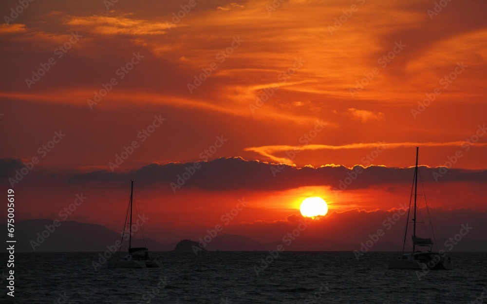 Scenic view of sailboats gliding across a tranquil body of water at sunset. Thailand, Railay Beach.