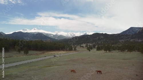 Aerial ascent backup of horses eating in ranch pasture with mountains in background, Rocky Mountains, Estes Park, Colorado photo