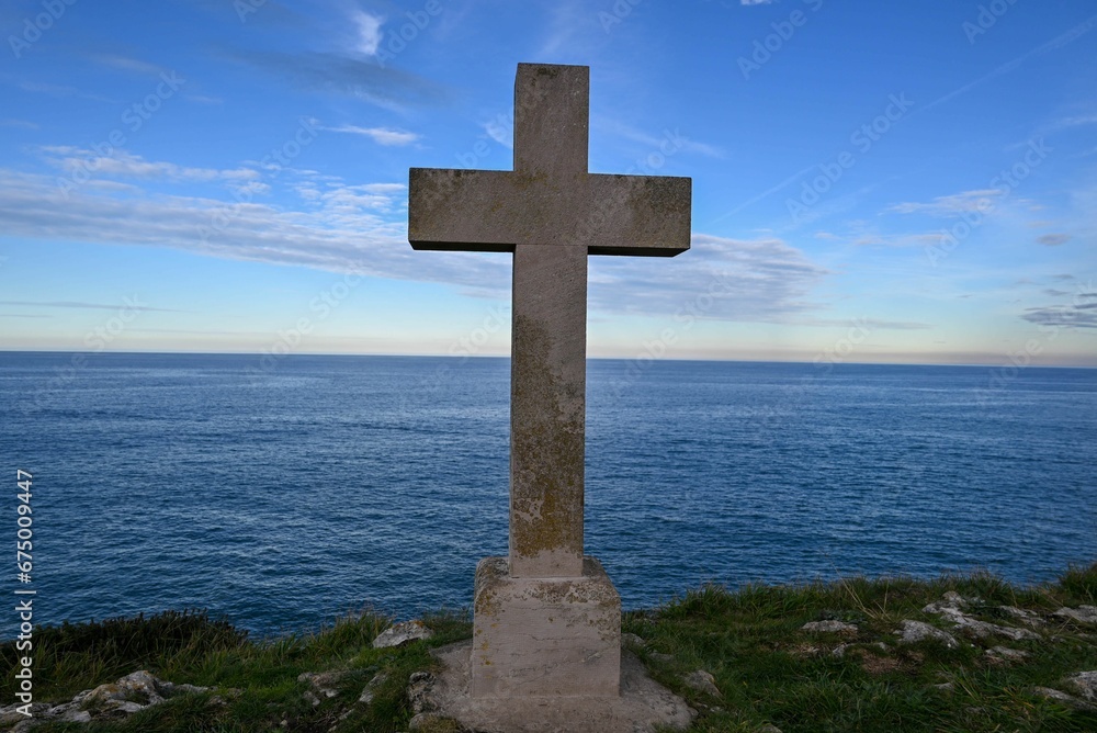 Wooden cross standing on the edge of a cliff with a dramatic sky backdrop