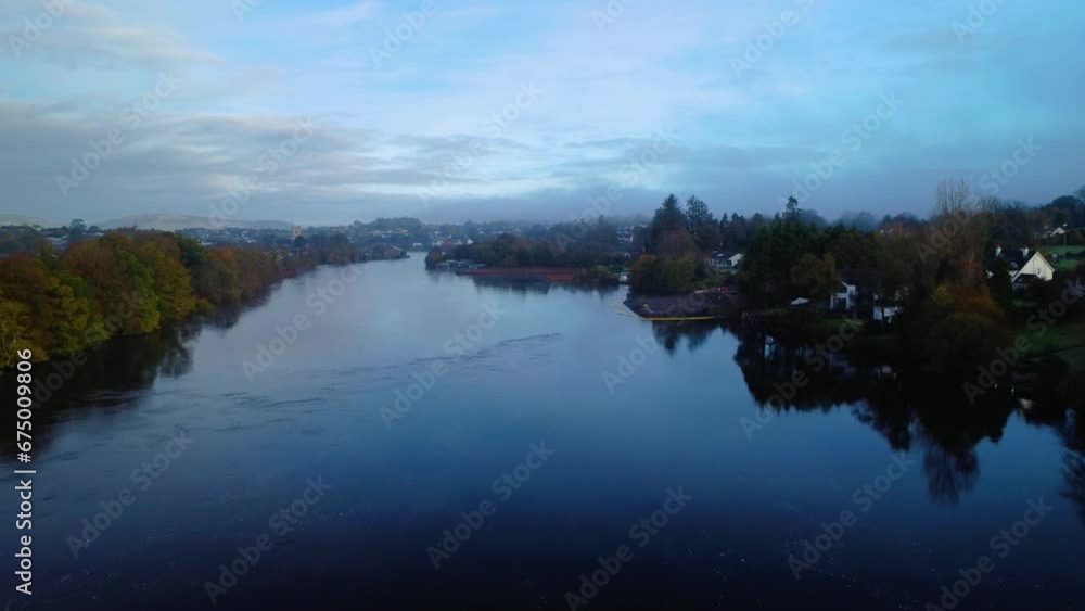 Aerial video of a calm lake surrounded by buildings on the shore on a foggy day Aerial video of a calm lake surrounded by buildings on the shore on a foggy day