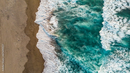 Aerial view of a coastal landscape with large waves crashing against a sandy beach