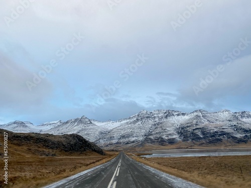 the long straight road in iceland with the mountains behind it