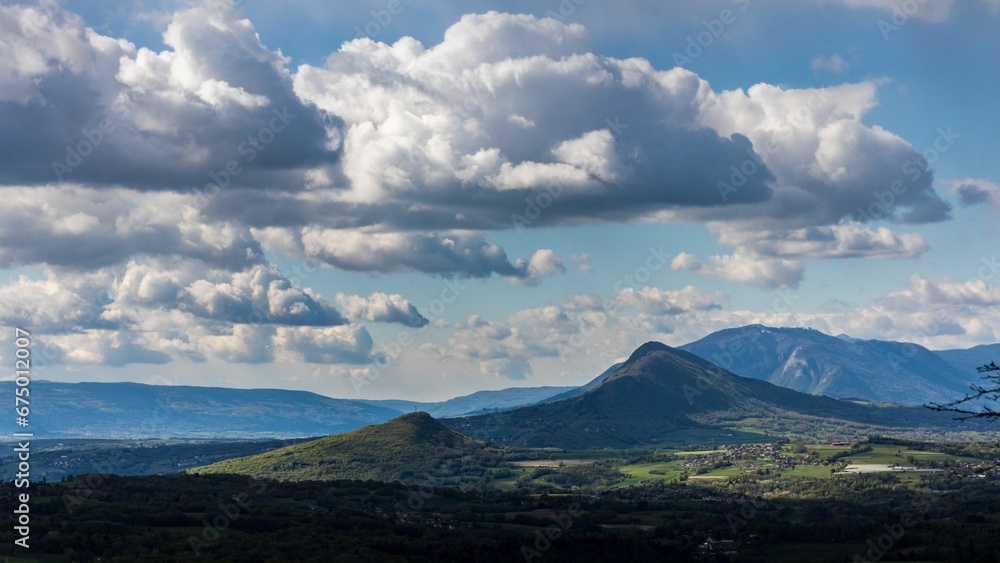 Tranquil landscape featuring a large mountain with a serene blue sky and white fluffy clouds.