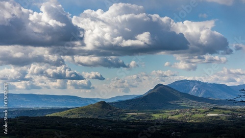 Tranquil landscape featuring a large mountain with a serene blue sky and white fluffy clouds.