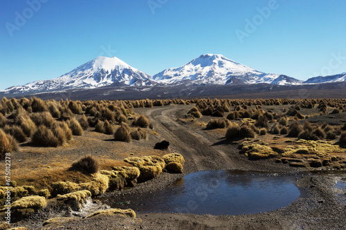 Landscape composed of a small stream and Parinacota and Pomerape volcanoes in the background photo