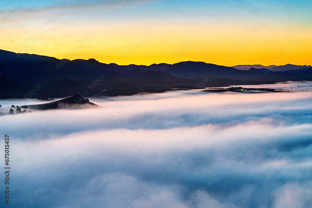 Cloud inversion over valley at sunrise, sunset, with mountains