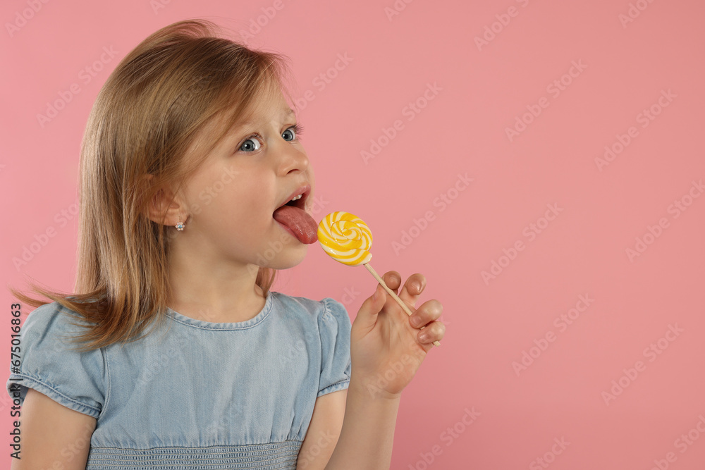Portrait of cute girl licking lollipop on pink background, space for text - obrazy, fototapety, plakaty 