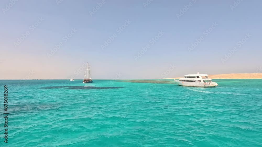 A frigate and a yacht in turquoise waters beyond the dunes of Egypt A frigate and a yacht in turquoise waters beyond the dunes of Egypt