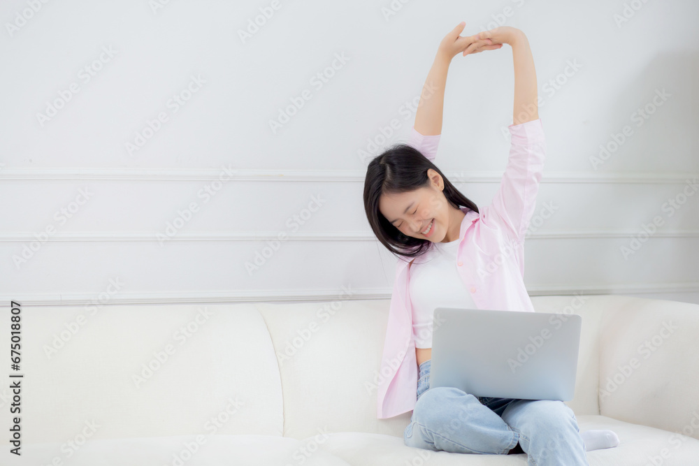 Beautiful young asian businesswoman sitting on sofa and working from home and break while stretch arm for relax in living room at home, woman is freelance working on laptop computer, business concept. Beautiful young asian businesswoman sitting on sofa and working from home and break while stretch arm for relax in living room at home, woman is freelance working on laptop computer, business concept.