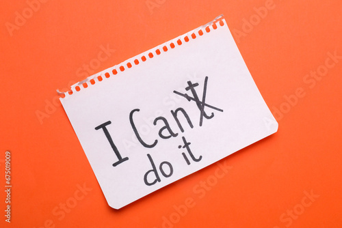 Motivation concept. Changing phrase from I Can't Do It into I Can Do It by crossing out letter T on orange background, top view