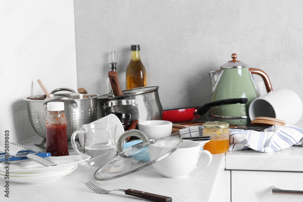 Many dirty utensils, cookware and dishware on countertop in messy kitchen Many dirty utensils, cookware and dishware on countertop in messy kitchen