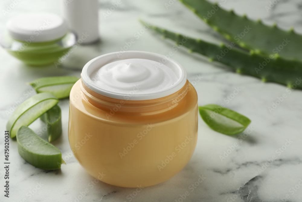 Jar with cream and cut aloe leaves on white marble table, closeup Jar with cream and cut aloe leaves on white marble table, closeup