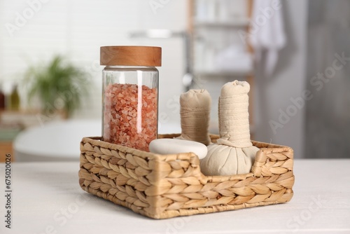 Composition with spa herbal bags on white table in bathroom, closeup