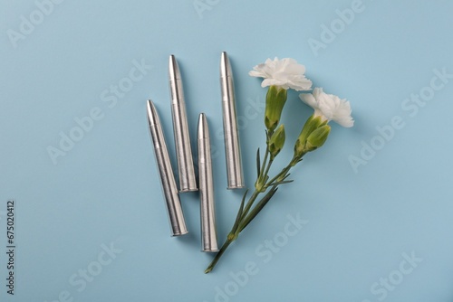 Bullets and beautiful flowers on light blue background  flat lay