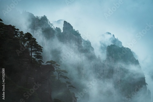 Breathtaking aerial view of majestic mountains with lush green treetops reaching towards the sky © Wirestock