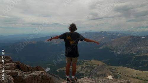 Cinematic man person at the top of Rocky Mountain National Park Colorado Denver Boulder Estes Park 14er Longs Peak looking out to Indian Peaks sunny cloudy late summer dramatic landscape still photo