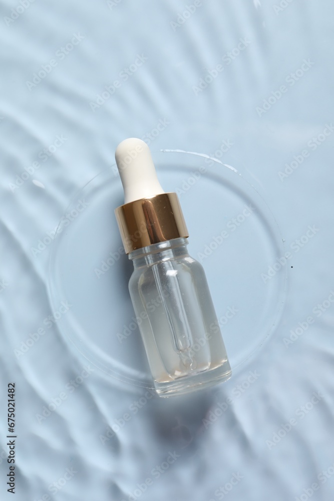 Bottle of cosmetic serum and water on light blue background, top view Bottle of cosmetic serum and water on light blue background, top view
