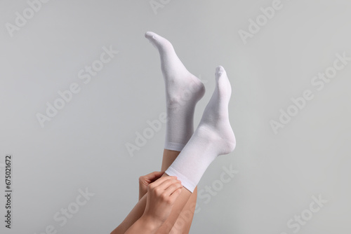 Woman in stylish white socks on light grey background, closeup