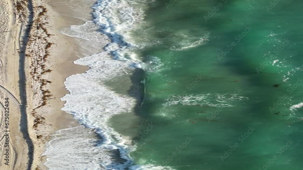 Aerial view of foamy waves covering a sandy coastline Aerial view of foamy waves covering a sandy coastline