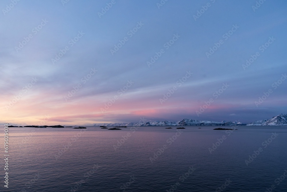 Serene sunset overlooking a tranquil body of water with mountains on the background