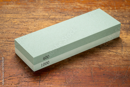 corundum dual-sided knife sharpening stone against grunge wood background