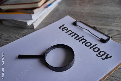 Closeup image of books, magnifying glass and paper clipboard with text TERMINOLOGY.