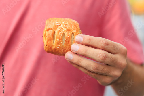 A guy's hand holds a mini puff pastry with cheese, snack and fast food concept. Selective focus on hands