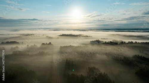Aerial view flying over remote forest covered in nordic morning haze