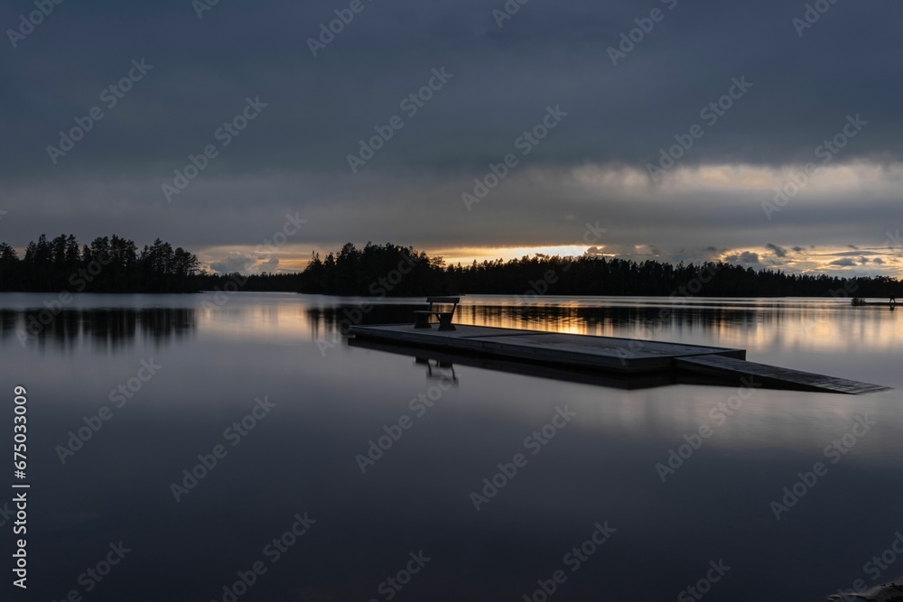 Tranquil lake is surrounded by a dark sky and billowing clouds.