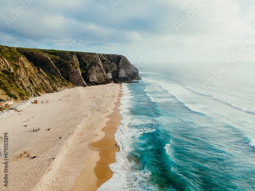 Foto Picturesque beach with a serene ocean backdrop, featuring a dramatic rocky cliff