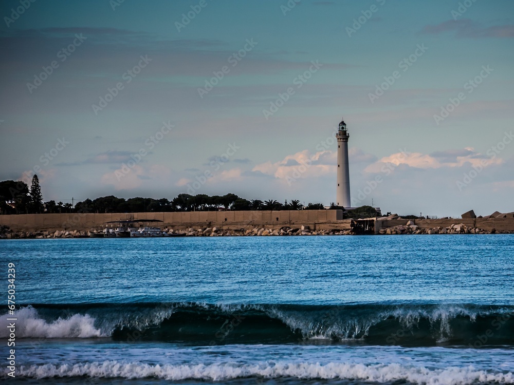 Tranquil scene of a lighthouse and shoreline, with waves gently lapping the shore Tranquil scene of a lighthouse and shoreline, with waves gently lapping the shore